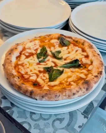Eine frisch gebackene Pizza Margherita auf dem Tellerstapel in der Küche