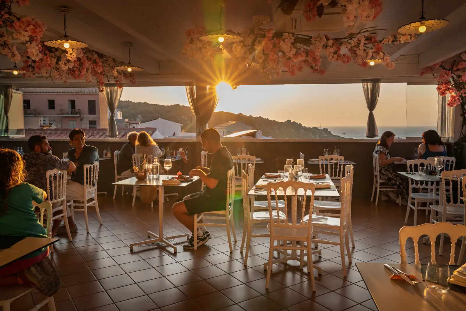 Die Terrasse bei Sonnenuntergang mit Gästen an den Tischen